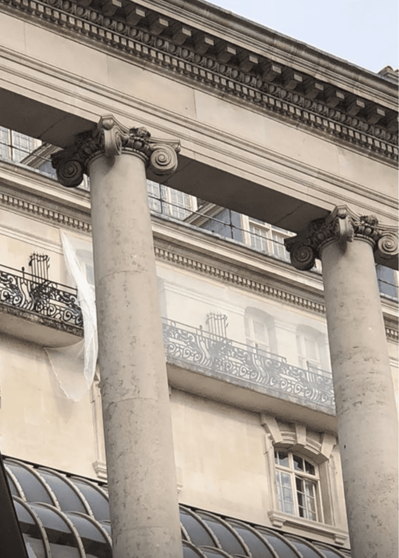 AAA rope technician in safety gear installing safety nets on a damaged building facade, performing stone repairs and addressing spalling concrete.